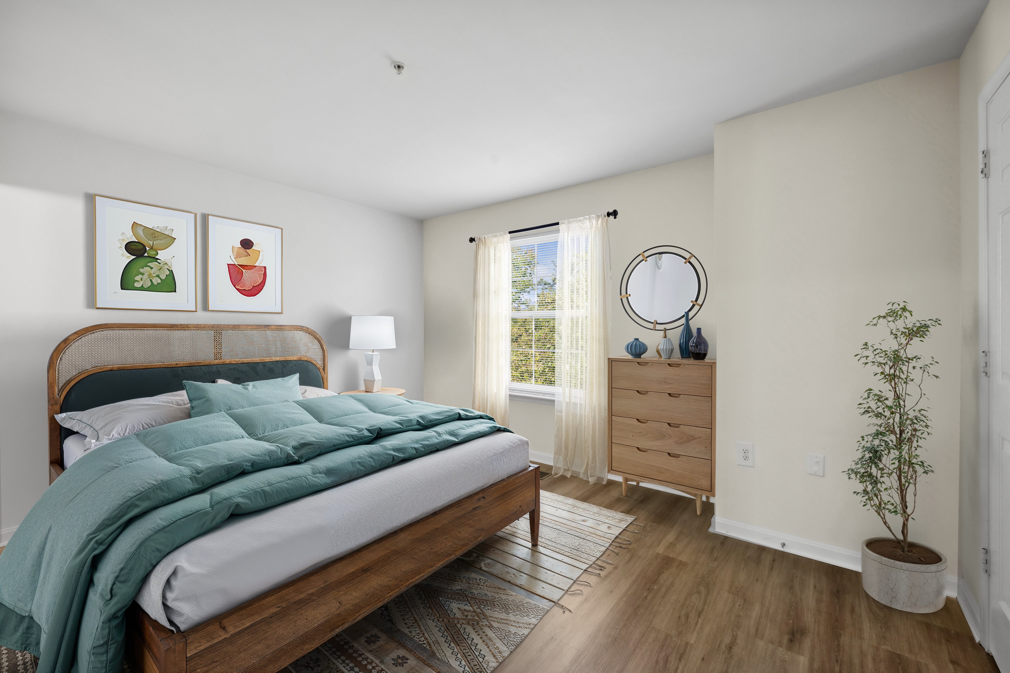 A bedroom with a bed, dresser, and plant.